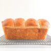 Whole loaf of bread on silver wire cooling rack.